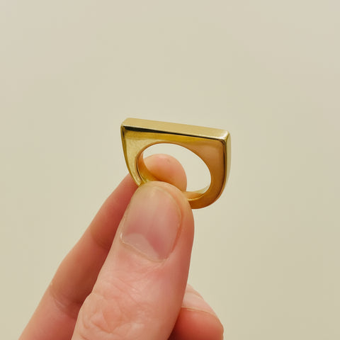 Gold ring held by a hand in a store setting