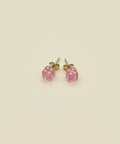 Pink square earrings on a wooden surface