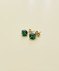 Green dice-shaped earrings on a wooden surface