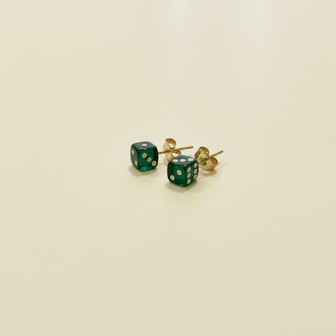 Green dice-shaped earrings on a wooden surface
