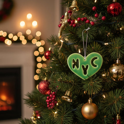 Green heart-shaped ornament with 'NYC' cutout on a wooden surface