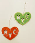 Two heart-shaped 'NYC' cutout charms on a wooden surface.