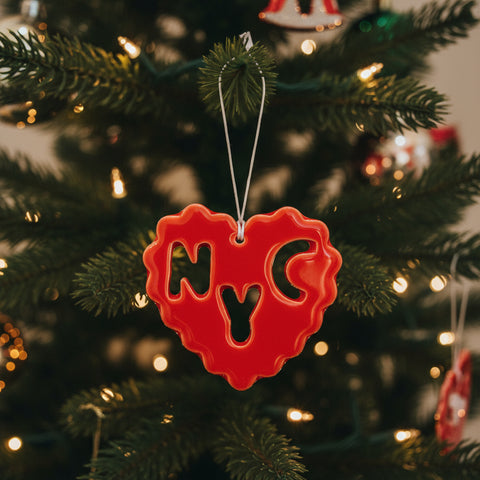 Red heart-shaped ornament with cut-out letters on a wooden surface