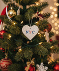 Heart-shaped ceramic tag with 'NYC' on a wooden surface