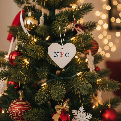 Heart-shaped ceramic tag with 'NYC' on a wooden surface