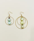 Pair of gold hoop earrings with pearl-like beads on a wooden surface