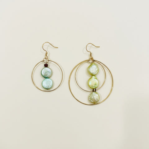 Pair of gold hoop earrings with pearl-like beads on a wooden surface