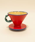 Red ceramic coffee filter on a wooden surface with a blurred background