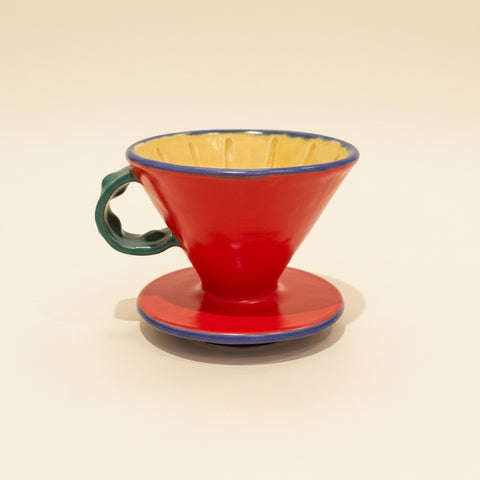 Red ceramic coffee filter on a wooden surface with a blurred background