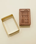 Rectangular cookie cutter and wooden stamp with architectural design on a wooden surface