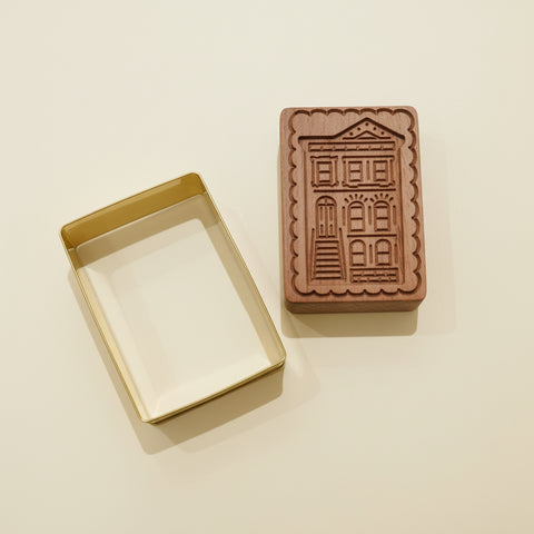 Rectangular cookie cutter and wooden stamp with architectural design on a wooden surface