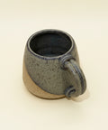 Speckled gray ceramic mug on a wooden surface