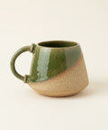 Green ceramic mug on a wooden table with a blurred background