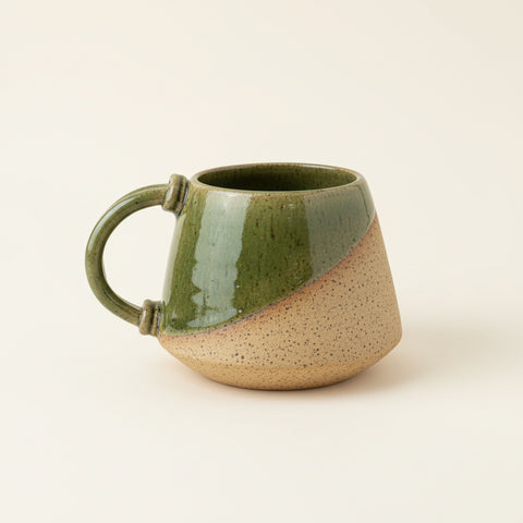 Green ceramic mug on a wooden table with a blurred background