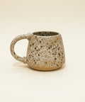 Speckled ceramic mug on a beige background