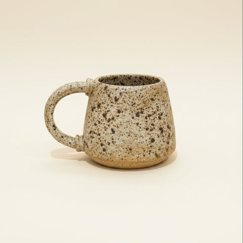 Speckled ceramic mug on a beige background