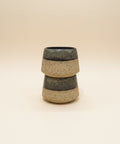 Stacked ceramic cups on a wooden table with a blurred office background