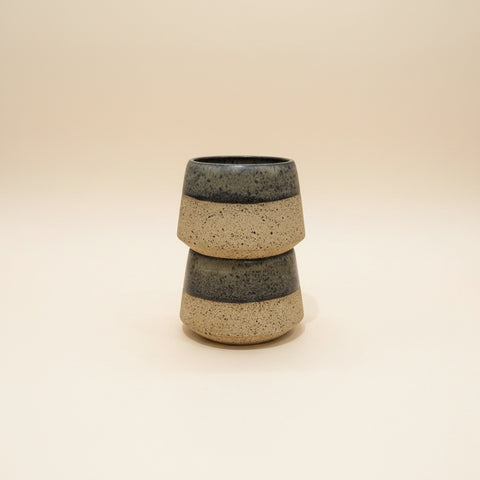 Stacked ceramic cups on a wooden table with a blurred office background