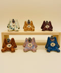 Set of ceramic rabbit figurines in various colors on a wooden stand.