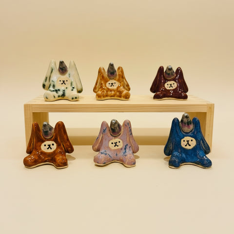 Set of ceramic rabbit figurines in various colors on a wooden stand.