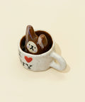 Small ceramic cup with a bear figurine inside on a wooden surface