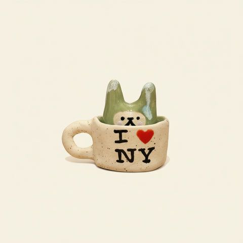 Small ceramic cup with a bear design and 'I ❤️ NY' text on a wooden surface.