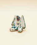 Small ceramic rabbit figurine with a smiling face on a wooden surface