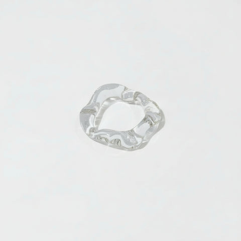 Clear glass ring with wavy design on a white background