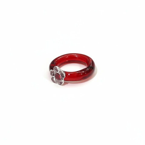 Red glass ring with a decorative element on a wooden surface