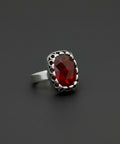 Silver ring with a red gemstone on a black background