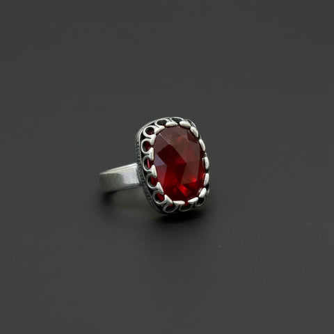 Silver ring with a red gemstone on a black background