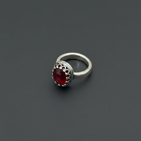 Silver ring with a red stone on a wooden surface