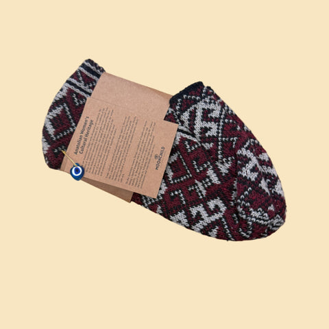 Pair of patterned socks with a brand tag on a wooden surface, next to a person wearing the socks.