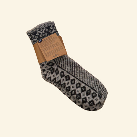 Black and gray patterned sock on a wooden desk next to a laptop