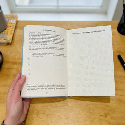 Open book titled 'My Happiness List' on a wooden surface
