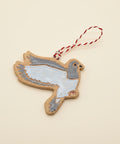 Decorative ceramic pigeon ornament with a string on a wooden surface