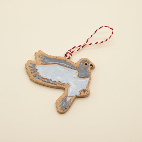 Decorative ceramic pigeon ornament with a string on a wooden surface