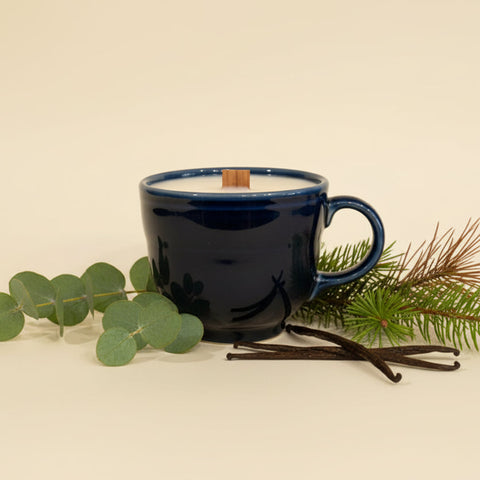 Blue mug with a wooden spoon on a wooden surface against a white wall with blue circular design.