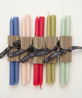 Set of colorful candles in cardboard holders with ribbons on a wooden surface