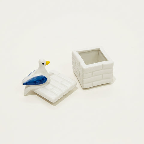 Small ceramic trinket box with a pigeon figurine attached to the top.