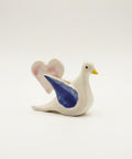 Decorative ceramic dove with blue wings on a wooden surface