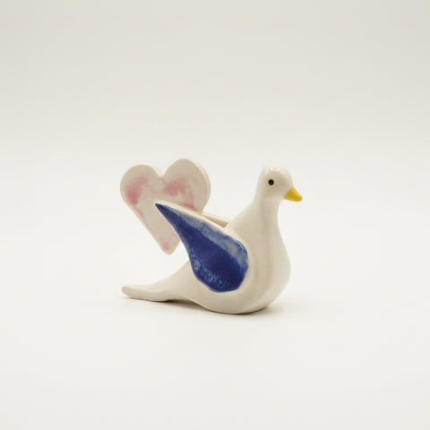 Decorative ceramic dove with blue wings on a wooden surface