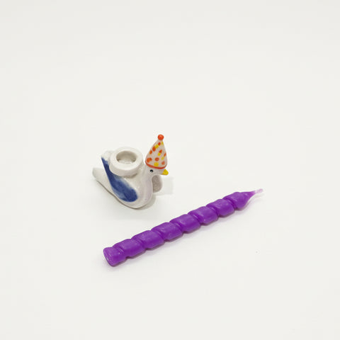 Small figurine with a purple candle-like object on a wooden surface