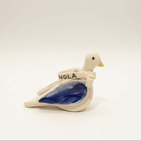 Decorative ceramic dove figurine on a wooden surface with a laptop in the background.
