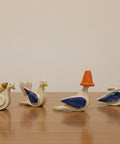 Set of ceramic duck-shaped items on a wooden surface with a white background