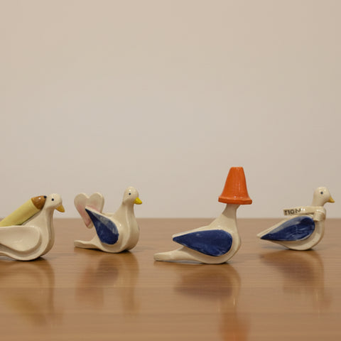 Set of ceramic duck-shaped items on a wooden surface with a white background
