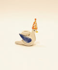 Small ceramic duck figurine with a party hat on a wooden desk.