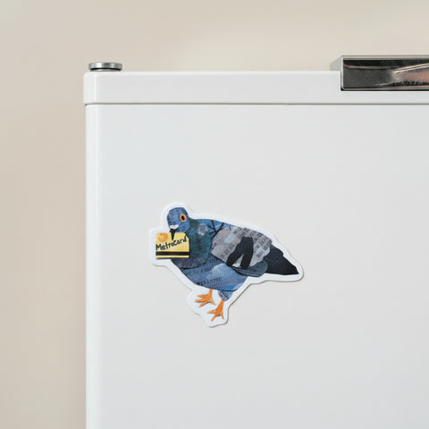 A die-cut sticker featuring a stylized pigeon collage made from blue denim, black-and-white newspaper print, and an orange beak and feet, holding a yellow Metrocard, shown on a plain light beige background.