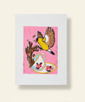 Colorful illustration of a bird and teacup on a pink background, framed and placed on a wooden surface.