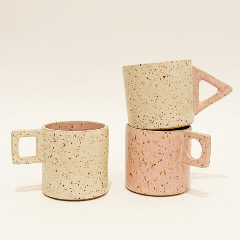 Three ceramic mugs stacked on a wooden surface with a blurred background